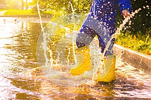 My rubber-booted feet are Bouncing in a puddle. Article about rubber boots. Children`s summer shoes. Puddles after rain. Bad