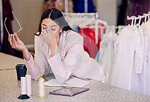 My shop is not doing as well as I hoped it would. a young seamstress looking stressed while working in a boutique.