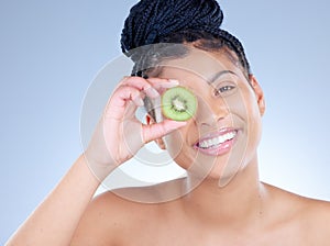My skin thanks me. Studio portrait of an attractive young woman holding a sliced kiwi against a blue background.