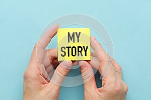 My story text on yellow notice paper on notepad or diary in hands