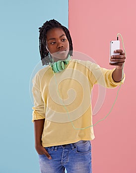 My style. A young boy with headphones around his neck taking a photo with his smartphone.