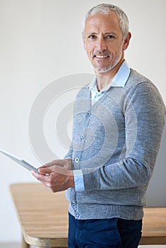 My tablet helps me to get even MORE work done. Portrait of a mature businessman using his digital tablet in the office.