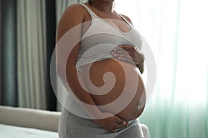 My tiny miracle. Closeup shot of an unrecognisable woman touching her pregnant belly at home.