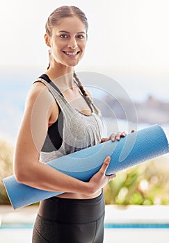 On my way to yoga class. Portrait of an attractive young woman carrying her yoga mat to class.