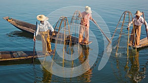 Myanmar, Inle Lake. Fishermen on boats demonstrate ancient way of fishing