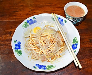 Myanmar traditional or classic thick round noodle salad called Nan Gyi Thohk recipe and a cup of