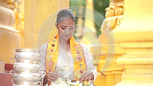 Myanmar women holding flowers at a temple. Southeast Asian young girls with burmese traditional dress visiting a Buddihist temple.