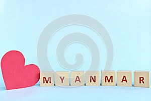 Myanmar word on wooden blocks with red heart shape cutout in blue background. Support, sympathy pray, and send love to Myanmar