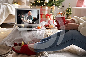 MYKOLAIV, UKRAINE - DECEMBER 25, 2020: Woman with sweet drink watching The Queen`s Gambit series on laptop at home, closeup. Cozy