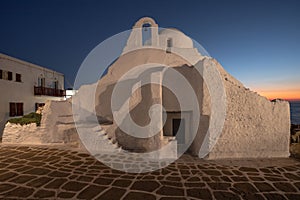 Mykonos, Greece, features an ancient church illuminated by the golden hues of a gorgeous sunset