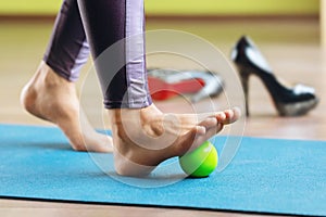 Myofascial relaxation of the hypermobile muscles of the foot with a massage ball, standing on a mat in the studio photo