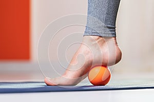 Myofascial relaxation of the muscles of the foot with a massage ball on a mat at home, close-up