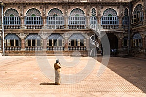 Mysore, India - December 10 2017: Yard in Mysore Palace with windows and arches with female security