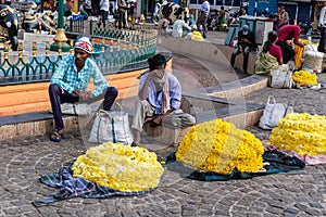 Indian street vendors selling garlands and flowers in a market square in the city of