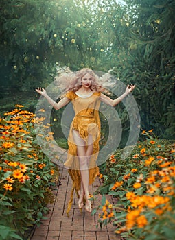 Mysterious attractive flower fairy in light yellow dress with long train and open legs in jump in the forest with bright