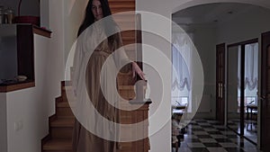 Mysterious barefoot Caucasian woman walking down the stairs indoors and leaving. Portrait of ghost in long dress in