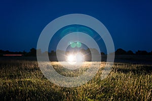 Mysterious bright headlights from a car. In a field on a summers night