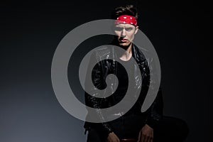 Mysterious fashion model wearing leather jacket on grey background