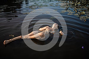 Mysterious And Fashion Portrait Of Young Woman Lying In Water