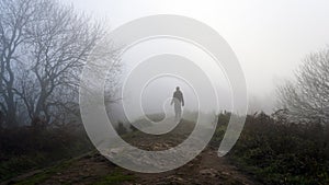 A mysterious figure. Silhouetted on a hill on a spooky, eerie foggy day. In the countryside in winter