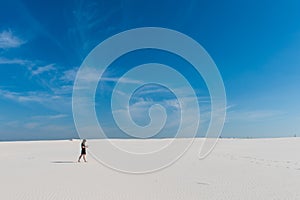 Mysterious girl walk far with aquarium in desert