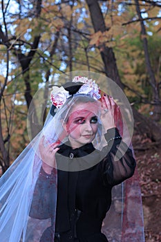 A mysterious Gothic woman in a long black Victorian dress and a white veil with blood. Halloween concept. A classic horror scene.