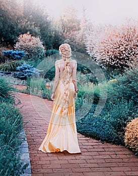 Mysterious lady in chic yellow expensive luxury dress in magnificent garden, mysterious princess with long blond hair