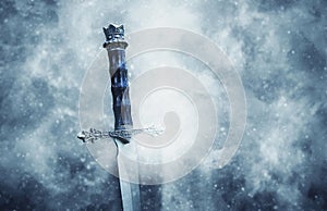 mysterious and magical photo of silver sword over gothic snowy black background. Medieval period concept.