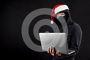 Mysterious male santa hacker holding laptop computer