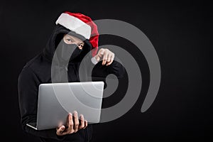 Mysterious male santa hacker holding laptop computer