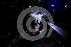 Mysterious man exhaling vaping smoke which hides its face while walking on the street during nighttime photo