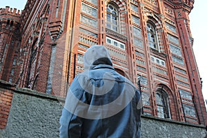 Mysterious man in hat is looking at the red colored building