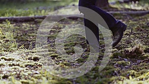 Mysterious man with a knife in his hands is on the ground in the woods. Visible large his feet are in motion.