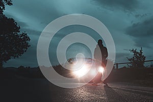 A mysterious man. Next to a car, silhouetted against car headlights On a cloudy summers evening. UK