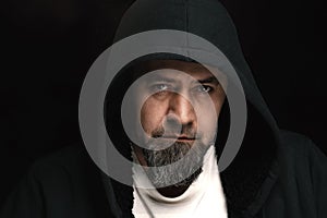Mysterious man wearing hoodies on a dark background. Handsome model wearing black hoodie on a plain black background