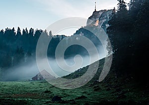 Mysterious mountain hut and tent during morning sunrise with fog