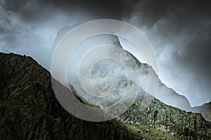 Mysterious mountain look with foggy weather and dark stormy sky.