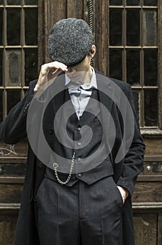 Mysterious portrait of retro 1920s english gangster with flat cap.