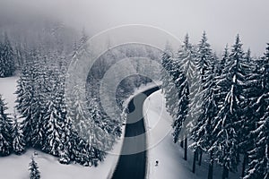Mysterious Winter road in the forest. Aerial view the a winding mountain road at Cheia, Romania