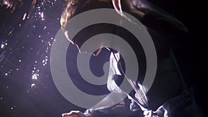 mysterious woman is floating under water surface, portrait shot against magic light underwater