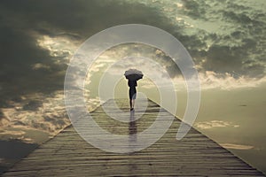 Mysterious woman with umbrella crosses a bridge to the threatening sky photo