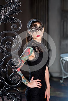 Mysterious woman in venetian carnival mask near wrought iron gate