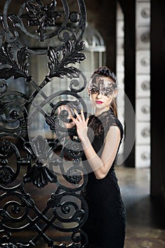 Mysterious woman in venetian carnival mask near wrought iron gate