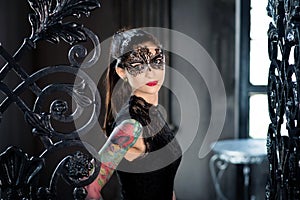 Mysterious woman in venetian carnival mask near wrought iron gate