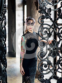 Mysterious woman in venetian carnival mask near wrought iron gate