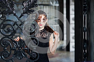 Mysterious woman in venetian carnival mask near wrought iron gate