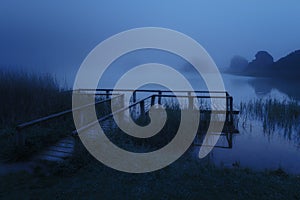 Mysterious wooden jetty on lake at night photo