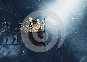 Mysteriousand magical image of old crown and book over gothic black background. Medieval period concept.