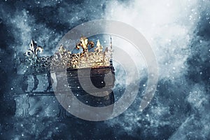 Mysteriousand magical image of old crown and book over gothic black background. Medieval period concept.