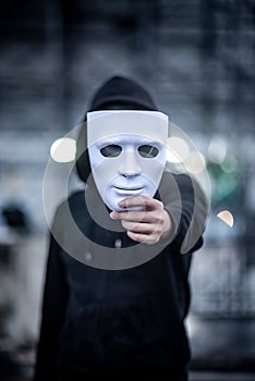 Mystery hoodie man holding white mask